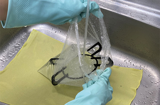 五徳など外せるパーツを袋に入れた後、アルカリ電解水をスプレーしてお湯を加え、浸け置きします